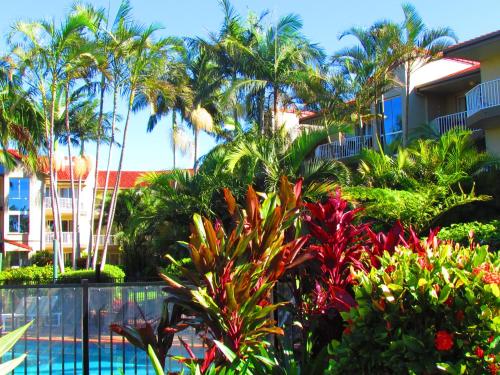 a garden in front of a building with palm trees at Bayview Waters Apartments in Gold Coast