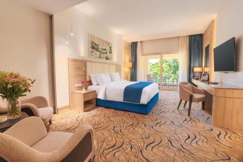 a hotel room with a bed and a desk and chairs at Helnan Antoniades Palace Hotel in Alexandria