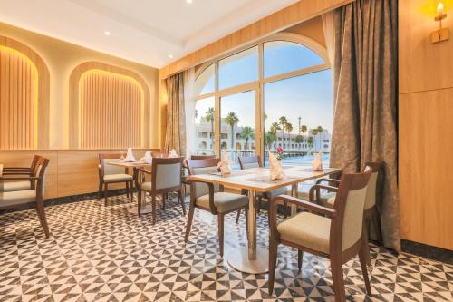 a restaurant with tables and chairs and a large window at Helnan Antoniades Palace Hotel in Alexandria