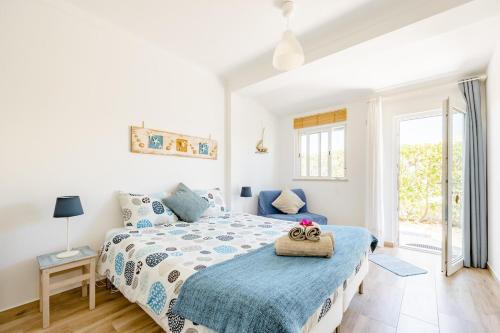 a white bedroom with a bed with a blue comforter at Onda Vicentina Guesthouse in Aljezur