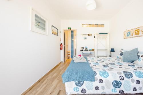 a bedroom with a bed with a blue and white comforter at Onda Vicentina Guesthouse in Aljezur