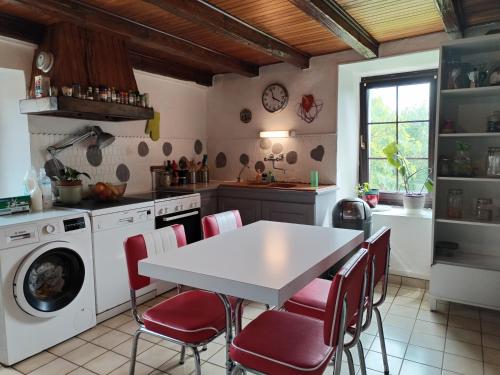 une cuisine avec une table blanche et des chaises rouges dans l'établissement La Maison du Noiret, à Cruseilles