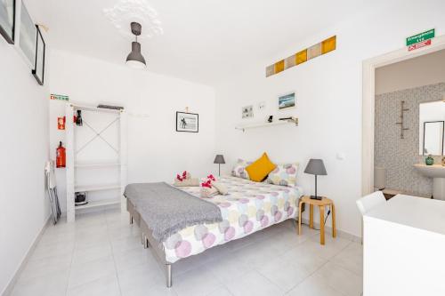 a white bedroom with a bed and a table at Onda Vicentina Guesthouse in Aljezur