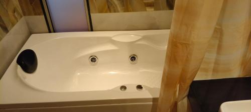 a white bath tub in a bathroom with a shower curtain at LuxePink Teddd Jucuzzi Studio-PrivatePatio in Gurgaon