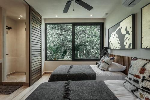 a bedroom with two beds and a large window at Ka'ana Condo in Tulum
