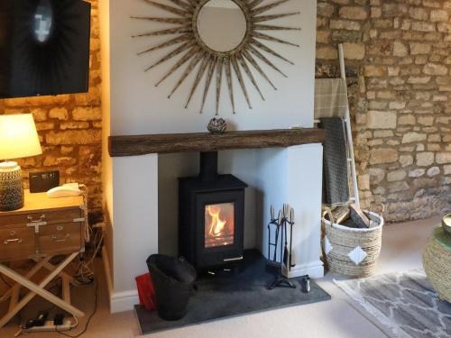 estufa de leña en la sala de estar con espejo en Yew Tree Cottage, en Broadway