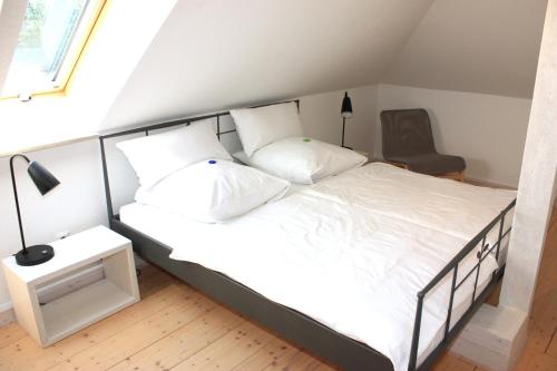 a bedroom with a bed with white sheets and a chair at Villa Brodthage, App. 1 in Walkenried