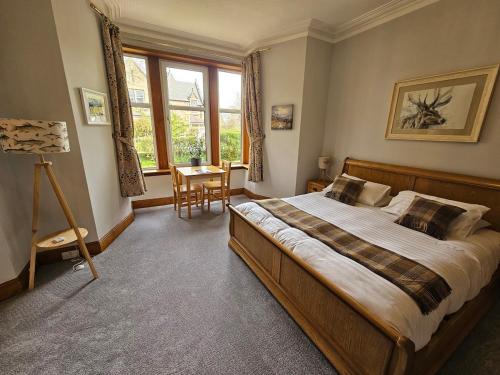 a bedroom with a large bed and a table at Fendoch Guest House in Inverness