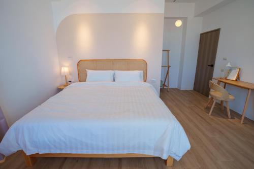 a bedroom with a large white bed and a desk at 與浪共舞 in Xiyu