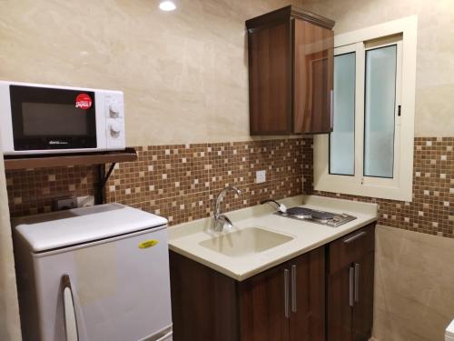 a small kitchen with a sink and a microwave at المهاجر للشقق المخدومة فرع قريش in Jeddah