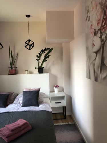 a bedroom with a bed and a painting on the wall at Komfortowy apartament Osiedle Lecha- garaż podziemny, balkon ,wejście 24h kod ,centrum, targi ,faktura in Kielce