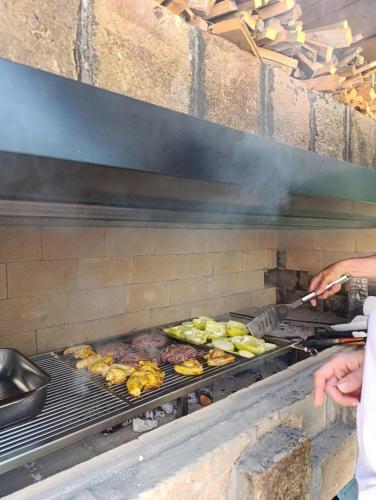 a person cooking meat and vegetables on a grill at Villa Green Heaven in Sarajevo