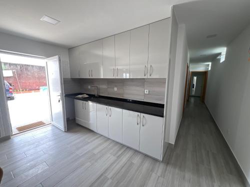 a kitchen with white cabinets and a wooden floor at Casa bernardino in Esmoriz