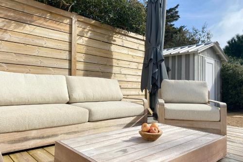patio con divano, tavolo e ombrellone di Villa Russie - Domaine Le Sherwood a Notre-Dame-de-Monts