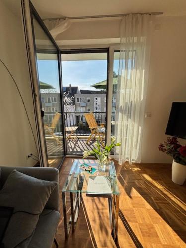 a living room with a glass table and a balcony at StellaStudio in Hamburg