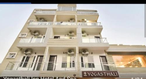 a tall white building with balconies and air conditioners at Hotel Yogasthali - Top Rated !! Most Awarded !! Luxury Rooms !! Lift !! Parking in Rishīkesh