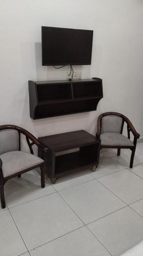 a living room with two chairs and a flat screen tv at Hotel Yogasthali - Top Rated !! Most Awarded !! Luxury Rooms !! Lift !! Parking in Rishīkesh