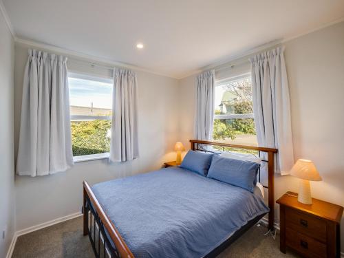 a bedroom with a bed and two windows at Cape View - Napier Holiday Home in Napier