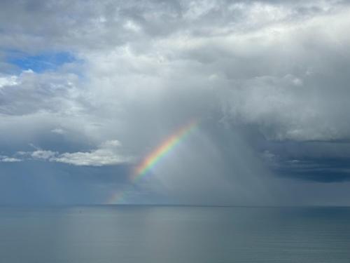 a rainbow in the sky over the water at Cape View - Napier Holiday Home in Napier