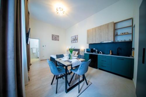a kitchen with a dining room table and blue chairs at H&H Luxury Apartments in Arad