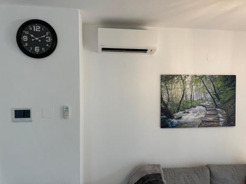 a clock hanging on a wall with a picture of a path at Luxus Urlaub auf 1000 Meter im Erholungsparadies in Liebenau