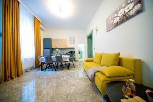 a living room with a yellow couch and a table at H&H Luxury Apartments in Arad