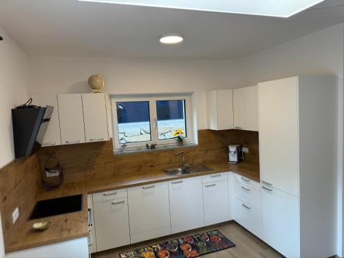 a kitchen with white cabinets and a window at Luxus Urlaub auf 1000 Meter im Erholungsparadies in Liebenau