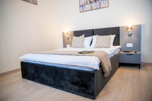 a bedroom with a large bed with a wooden headboard at H&H Luxury Apartments in Arad