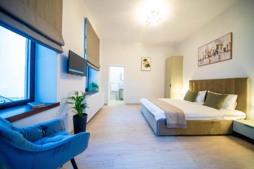 a bedroom with a large bed and a blue chair at H&H Luxury Apartments in Arad