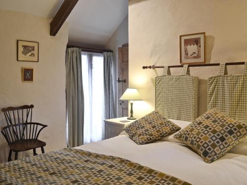 a bedroom with a bed and a chair and a window at Ty Christian in Blaencelyn