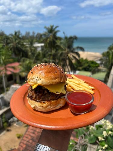 a plate of food with a hamburger and french fries at Surfing Tusker - Arugambay in Arugam Bay