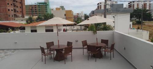 a patio with tables and chairs and umbrellas on a roof at Flat Hera 901 - Wi-fi, Vista mar a 300m da praia in Cabedelo