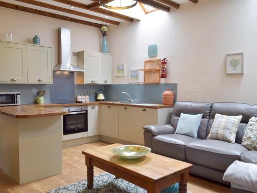 a kitchen and living room with a couch and a table at Old Rectory Cottage - Dinas Country Club in Dinas
