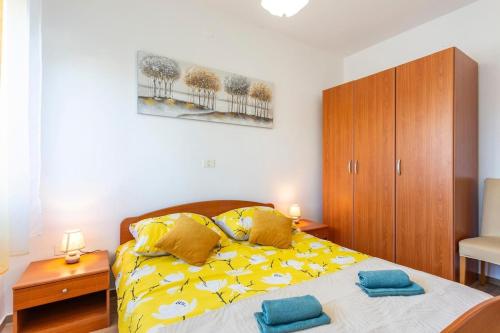 a bedroom with a yellow bed with two towels on it at Apartment Mattinna in Manjadvorci