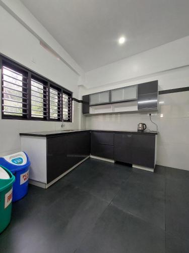 a kitchen with black cabinets and a sink and windows at Achandy Arcade in Kakkadampoyil
