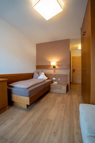 a bedroom with a bed and a light on the ceiling at Hotel Garni Savoy - new opening in Castelrotto