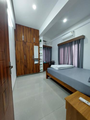 a bedroom with a bed and wooden cabinets at Achandy Arcade in Kakkadampoyil