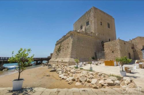 un grande edificio in pietra con alberi di fronte di L' Azzurro Mare casa vacanze a Pozzallo