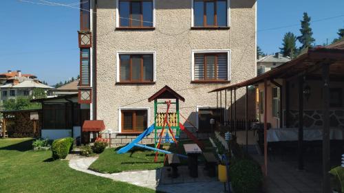un parque infantil frente a una casa con tobogán en Villa Silvinka, en Dospat