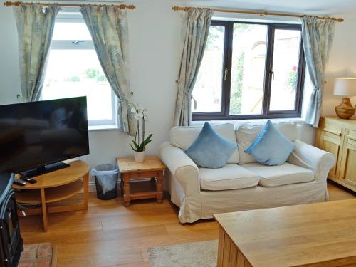 a living room with a white couch and a tv at The Cottage in Cheltenham