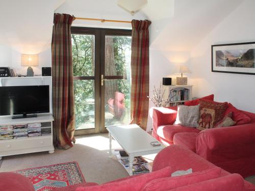 a living room with a red couch and a tv at Tarnside in Elterwater