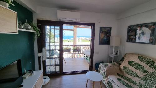 un soggiorno con divano e una porta che conduce a un balcone. di Apartamento 309 frente al mar en Alcossebre ad Alcossebre