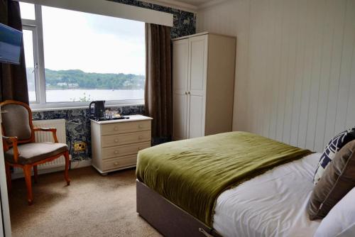 a bedroom with a bed and a desk and a window at Lochnell Arms Hotel in Oban