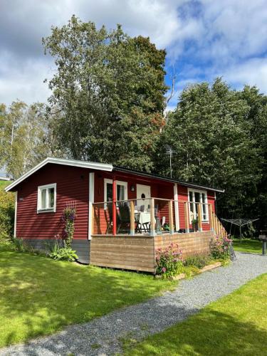 a red house with a porch on a lawn at Sommarstuga med sjötomt och brygga in Hedemora