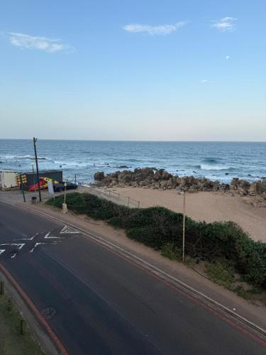 an empty road next to a beach with the ocean at Unit 124 Camarque , Umdloti in Umdloti