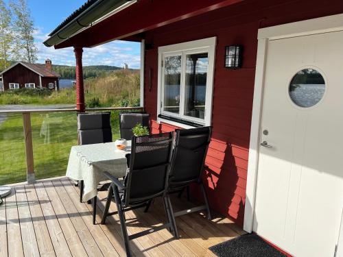 a patio with a table and chairs on a deck at Sommarstuga med sjötomt och brygga in Hedemora
