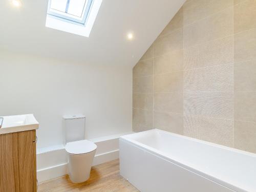 a bathroom with a white tub and a toilet at Kestrel Barn-Uk31353 in Swaffham