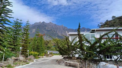 a house on a road with a mountain in the background at Sling & Stone Mountain Suites in Kundasang