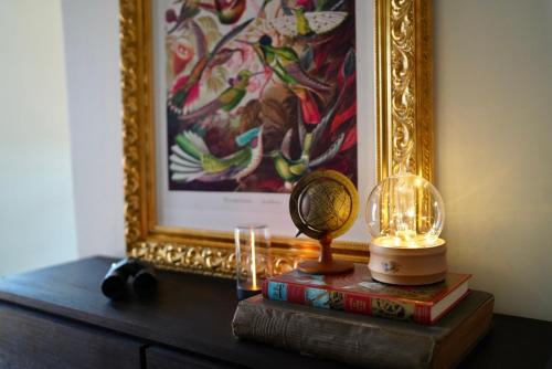 une table avec une photo, une lampe et des livres dans l'établissement Chambre privée - Le Boudoir Tropical, à Hendaye