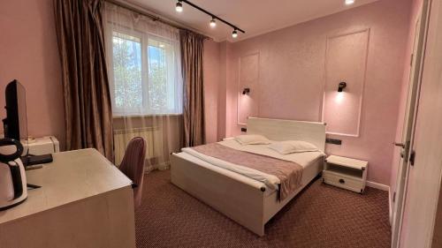 a bedroom with a bed and a desk and a window at JEPPESEN RESIDENCE in Almaty